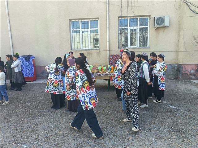 Milliy liboslardagi qizlar bayram dasturxoni yonida